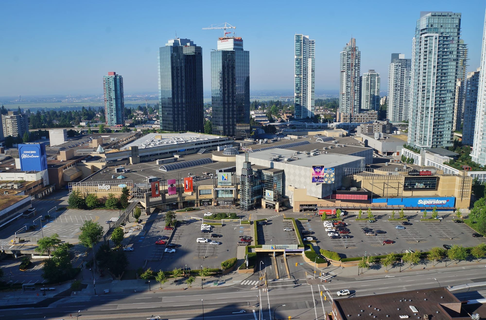 The north entrance of Metropolis at Metrotown shopping centre in Burnaby, with surrounding residential high-rise towers and the Expo Line SkyTrain visible.