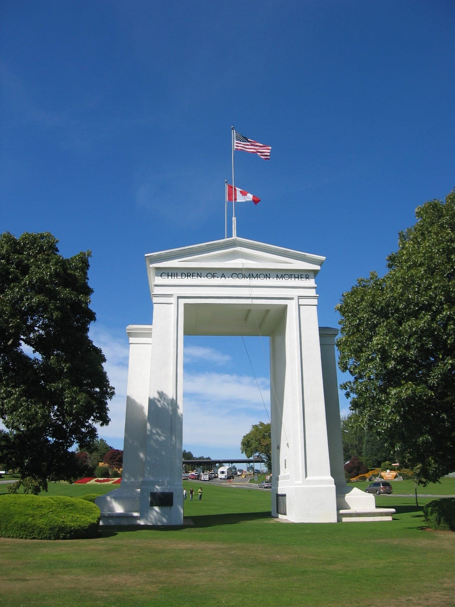The white marble Peace Arch monument straddling the border between British Columbia and Washington State, with landscaped gardens on either side.