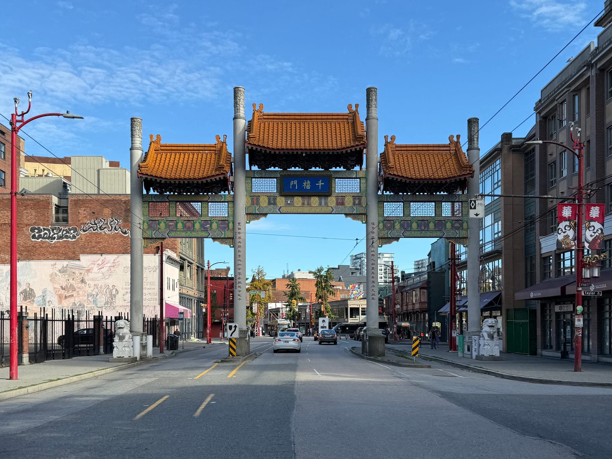 The ornamental Millennium Gate at the entrance of Vancouver's Chinatown on Pender Street, with green-tiled roof and red columns.